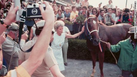 Fans look on as owner Penny Chenery gives Triple Crown winner Secretariat a pat.