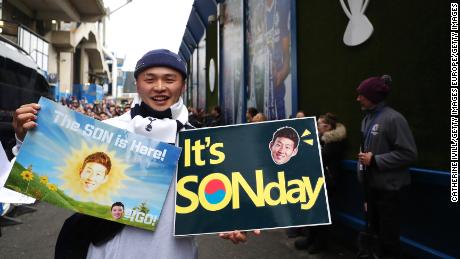 A Tottenham fan poses for a photo with his Son themed posters.