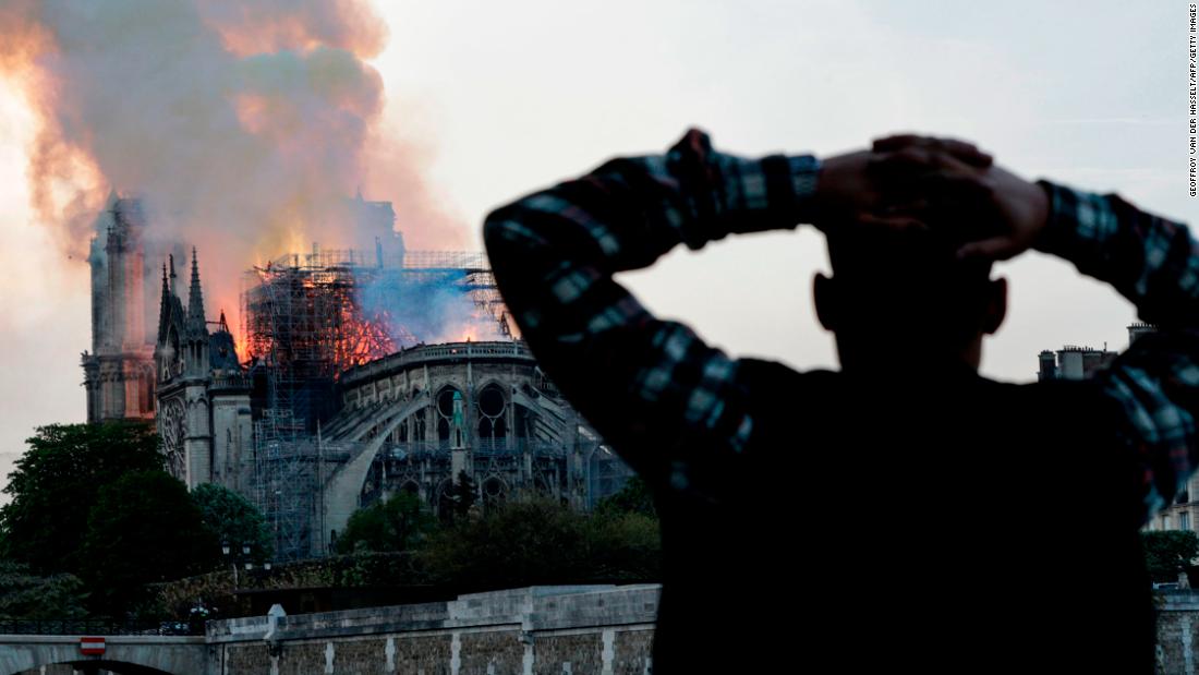 A man holds his head in shock as watches the fire take hold.