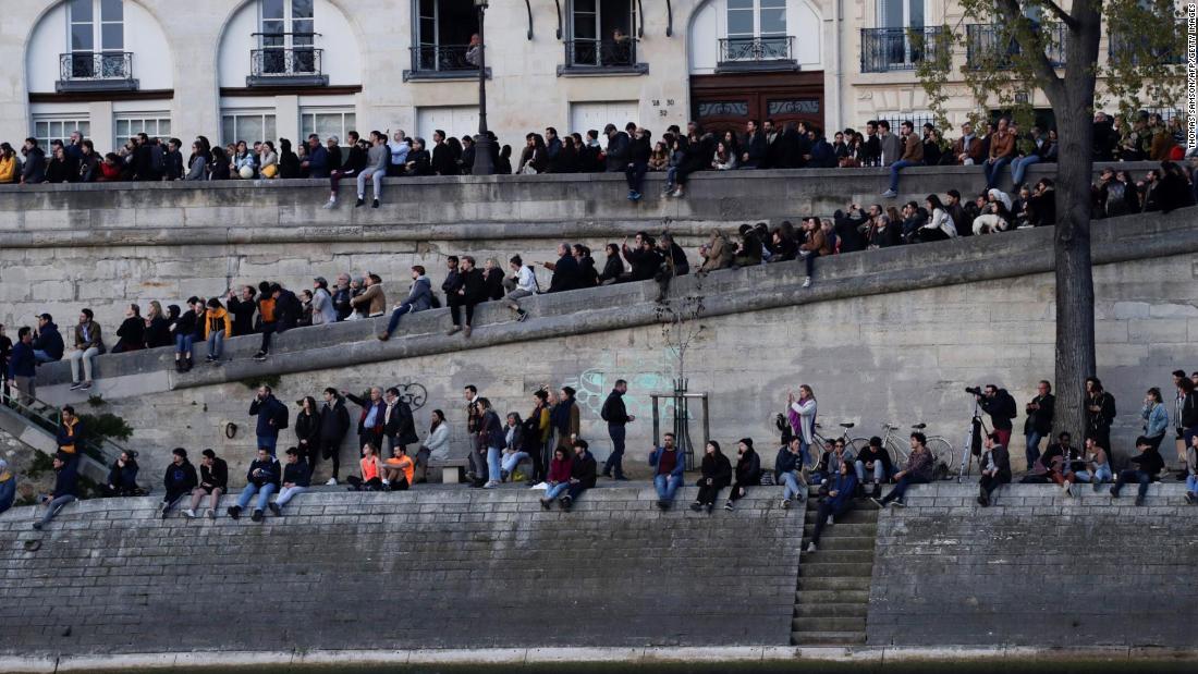 People gather on the banks of the Seine to watch the fire&#39;s progress.