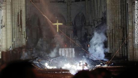 Smoke rises in front of the altar cross at Notre-Dame Cathedral in Paris on April 15, 2019, after a fire engulfed the building. - A huge fire swept through the roof of the famed Notre-Dame Cathedral in central Paris on April 15, 2019, sending flames and huge clouds of grey smoke billowing into the sky. The flames and smoke plumed from the spire and roof of the gothic cathedral, visited by millions of people a year. A spokesman for the cathedral told AFP that the wooden structure supporting the roof was being gutted by the blaze. (Photo by PHILIPPE WOJAZER / POOL / AFP)        (Photo credit should read PHILIPPE WOJAZER/AFP/Getty Images)