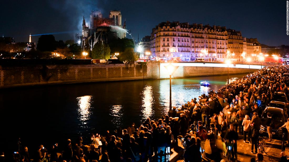 Crowds gathered on the banks of the Seine watch the firefighters&#39; progress.