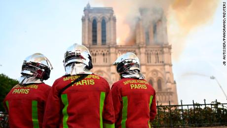 Firefighters stand near Notre Dame.