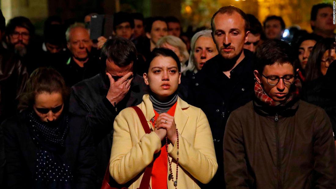 People pray as Notre Dame Cathedral burns on Monday evening.