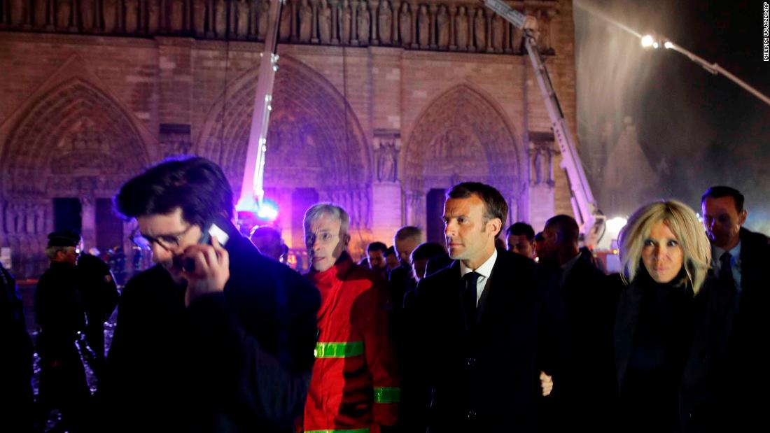 French President Emmanuel Macron, center, and his wife Brigitte at the scene of the fire on Monday evening.