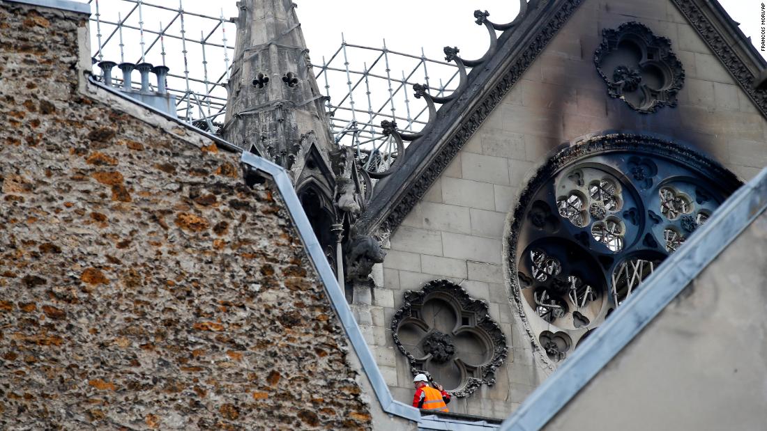 A man inspects damage near charred windows.