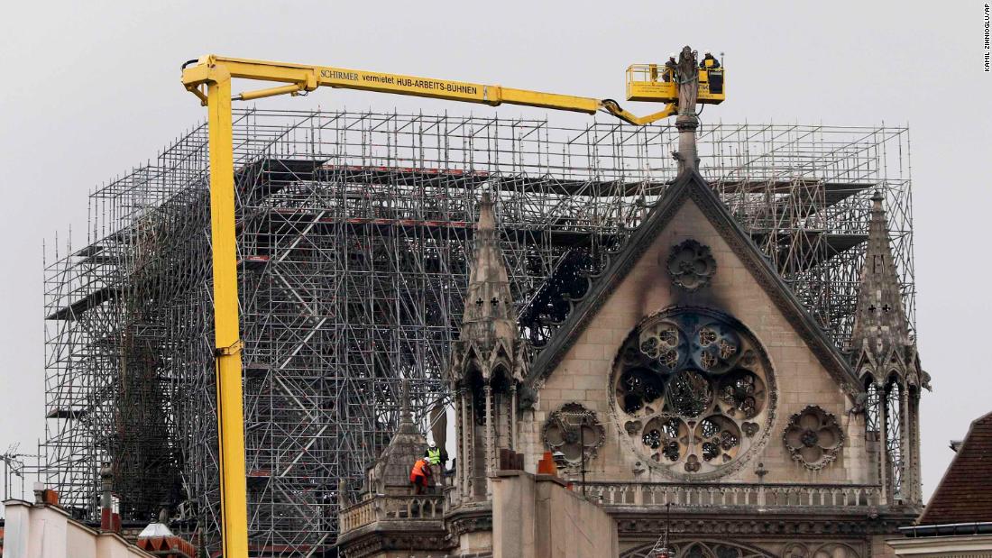 A crane lifts experts as they inspect the damage.