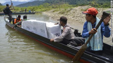 Indonesian election officials transport ballot boxes to a remote village by boat along a river in Manggamat, Southern Aceh province on April 16, 2019.