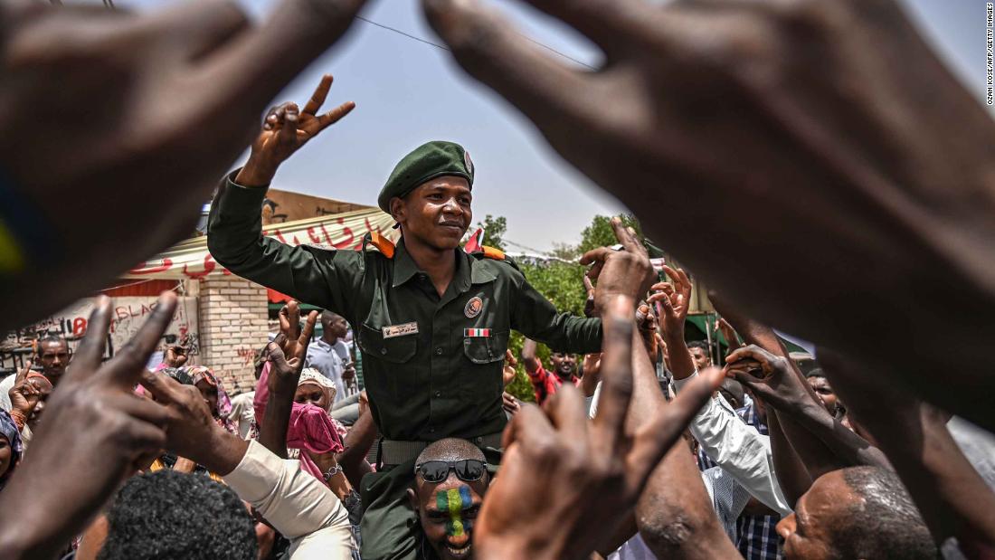 Protesters shout slogans as they carry a soldier flashing the victory sign outside the army headquarters on April 18.