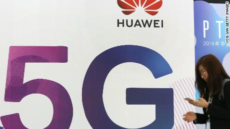 A woman walks past the stand of Huawei featuring 5G technology during the PT Expo China at Beijing National Convention Center.