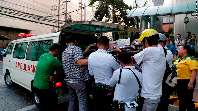 Workers carry an employee to an ambulance after she became dizzy when the earthquake hit Manila.