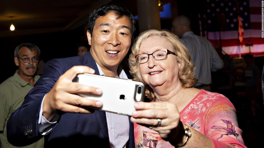 In August 2018, Yang takes a selfie with an attendee of the Democratic Wing Ding event in Iowa.