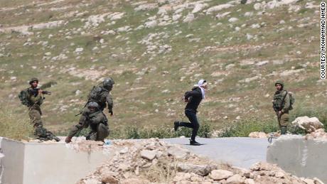 Palestinian teenager Osama al-Badan attempts to flee Israeli soldiers, blindfolded and handcuffed.