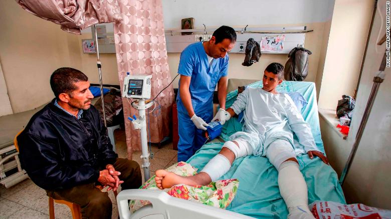 Al-Badan (right) receives treatment at Beit Jala Hospital near Bethlehem, as his father (left) looks on.