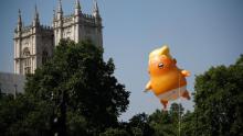 Pedestrians walk past as a giant balloon depicting US President Donald Trump as an orange baby floats next to the towers of Westminster Abbey during a demonstration against Trump&#39;s visit to the UK in Parliament Square in London on July 13, 2018. 