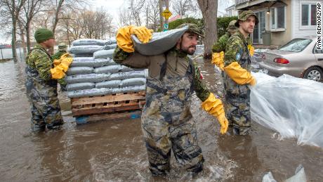 Canadian Forces personnel sandbag a house against floodwaters Thursday in Laval, Quebec.