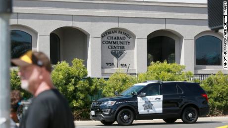 Neighborhood residents and members of the media stand before the Chabad of Poway Synagogue.