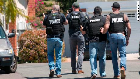 Heavily armed San Diego police officers approach a house thought to be the home of the suspect.