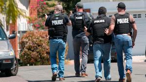 Heavily armed San Diego police officers approach a house thought to be the home of 19 year-old John T. Earnest, who is a suspect in the shooting of several people in a Poway synagogue, on Saturday, April 27, 2019, in San Diego, Calif. A gunman used an AR-type assault weapon to shoot worshippers at Chabad of Poway, San Diego County Sheriff William Gore said. (John Gibbins/The San Diego Union-Tribune via AP)