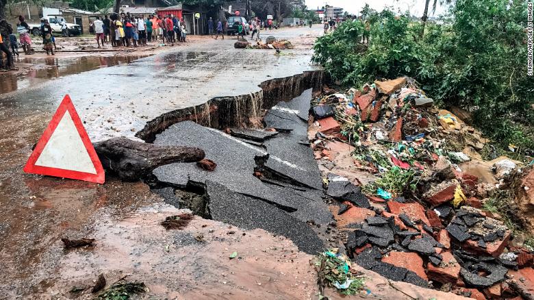 Residents stand next to a road partially destroyed by floods after heavy downpours in the Mozambican city of Pemba Sunday.