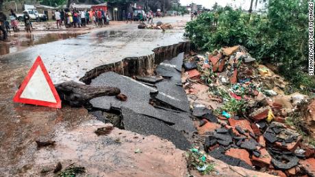 Residents stand next to a road partially destroyed by floods after heavy downpours in the Mozambican city of Pemba Sunday.