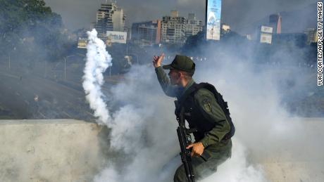 TOPSHOT - A member of the Bolivarian National Guard supporting Venezuelan opposition leader and self-proclaimed acting president Juan Guaido throws a tear gas canister during a confrontation with guards loyal to President Nicolas Maduro&#39;s government in front of La Carlota military base in Caracason April 30, 2019. - Guaido said on Tuesday that troops had joined his campaign to oust President Nicolas Maduro as the government vowed to put down what it called an attempted coup. (Photo by Yuri CORTEZ / AFP)        (Photo credit should read YURI CORTEZ/AFP/Getty Images)