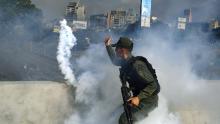 TOPSHOT - A member of the Bolivarian National Guard supporting Venezuelan opposition leader and self-proclaimed acting president Juan Guaido throws a tear gas canister during a confrontation with guards loyal to President Nicolas Maduro&#39;s government in front of La Carlota military base in Caracason April 30, 2019. - Guaido said on Tuesday that troops had joined his campaign to oust President Nicolas Maduro as the government vowed to put down what it called an attempted coup. (Photo by Yuri CORTEZ / AFP)        (Photo credit should read YURI CORTEZ/AFP/Getty Images)