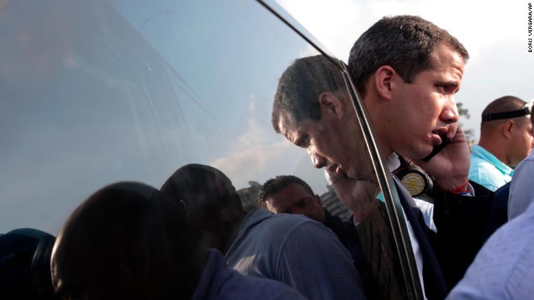 Guaido speaks on his cell phone outside La Carlota airbase where loyalist soldiers are based in Caracas.