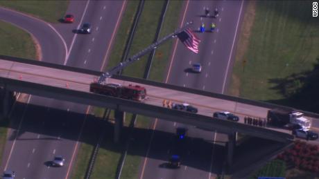 A vehicle carrying Howell&#39;s body back to his hometown Thursday, escorted by police, goes under an overpass where a fire crew raised a US flag in tribute.