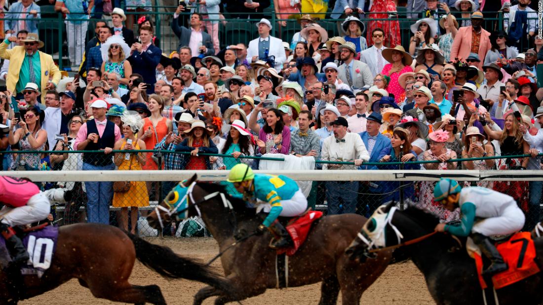 People cheer as they watch a race at Churchill Downs before the 145th running of the Kentucky Derby.