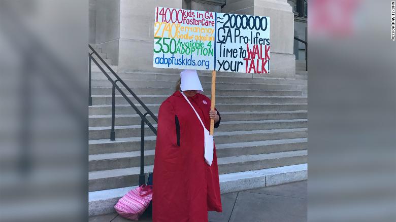A woman dressed in a red cloak evoking &quot;The Handmaid's Tale&quot; protests outside Georgia's Capitol.