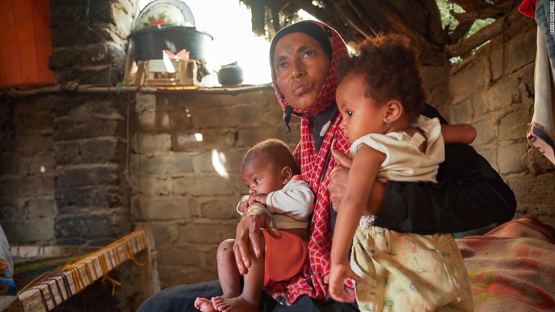 Issham Beshir sits on her mother&#39;s lap with her younger brother inside their hut in the village of Bani Qais.