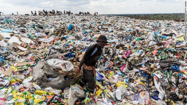 A recycler drags a huge bag of paper through a heap of non-recyclable waste in Zimbabwe.