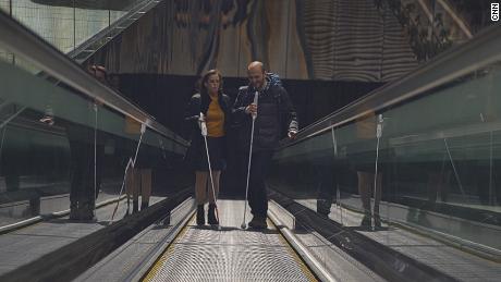 Kursay Ceylan (right) uses the WeWalk smart stick on his way to work