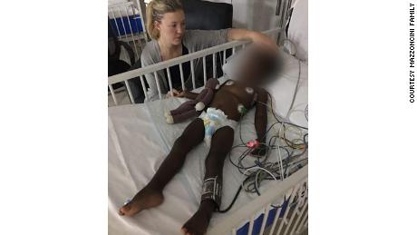 Daisy sitting by Kiano&#39;s bedside at the hospital. He has been treated multiple times for seizures. 