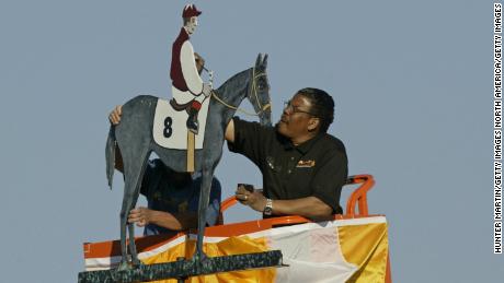 An artist paints the winning colors on the weather vane at Pimlico Race Track after the Preakness Stakes.