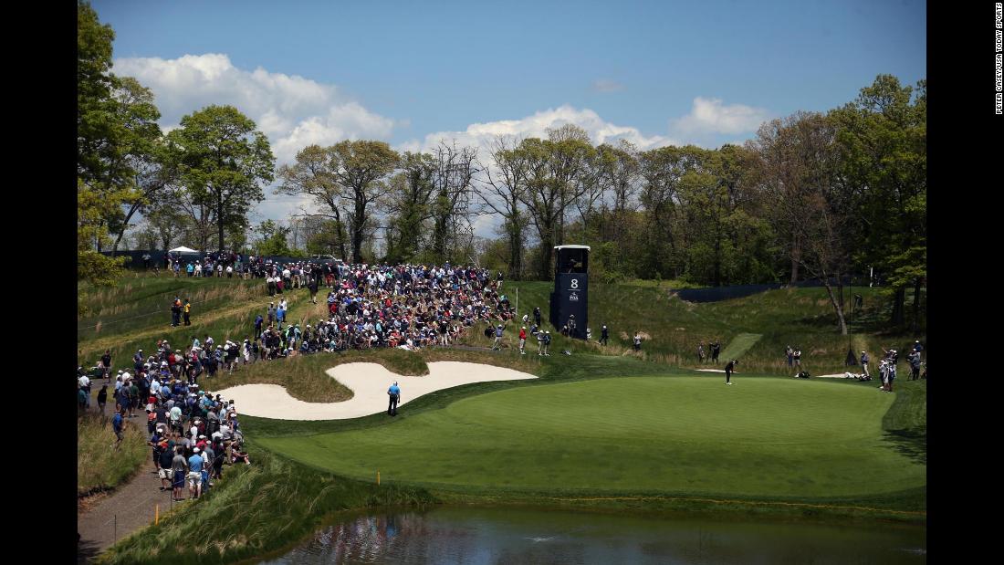 Brooks Koepka putts on a hulking eighth green, watched by fans who were witnessing a clinic from the three-time major winner.