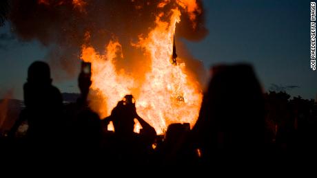 People watch as a temporary art installation burns in Coral Springs, Florida. 