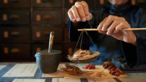 Man measuring ingredients in traditional Asian apothecary 