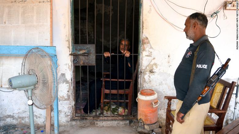 Muzaffar Ghanghro, a Pakistani pediatrician alleged to have been responsible for the HIV outbreak, sits behind bars as a policeman looks on at a local police station in Rato Dero in southern Sindh province on May 9, 2019. 