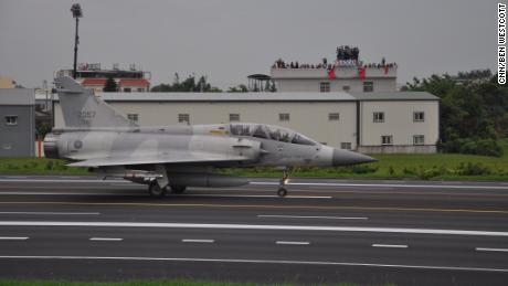 A Taiwan Mirage 2000 jet prepares to take off on a highway, during an exercise outside Taichung on Tuesday. In the background, onlookers wave the Taiwan flag.