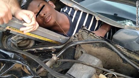 A man squeezed into a compartment built behind a car dashboard.