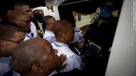 Booker&#39;s friends say a final goodbye to her casket in the hearse after her funeral service.