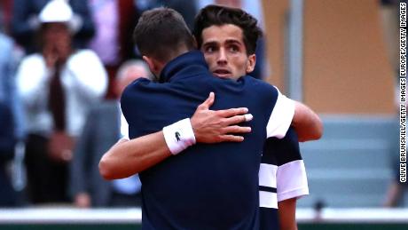 Pierre Hugues-Herbert (facing camera) and Benoit Paire embrace after their battle at the French Open. 