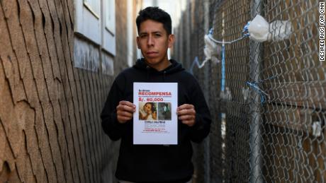 Carlos Jr. holds a reward flyer in the Brooklyn alleyway where he last saw his missing sister in person.