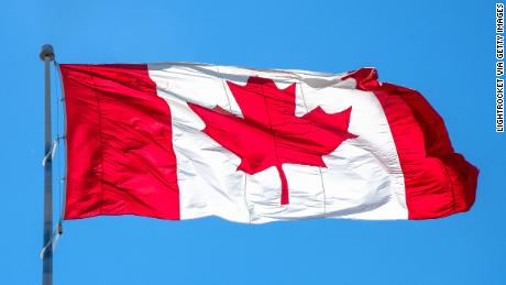 Flag of Canada or Canadian flag waving on blue clear sky.