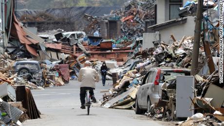 A resident cycles on the street amongst tsunami generated debris in Kamaishi, Iwate prefecture on May 6, 2011. The March 11 earthquake and subsequent tsunami left some 26,000 dead or missing and obliterated whole towns and villages on the northeast coast.    AFP PHOTO / TOSHIFUMI KITAMURA (Photo credit should read TOSHIFUMI KITAMURA/AFP/Getty Images)