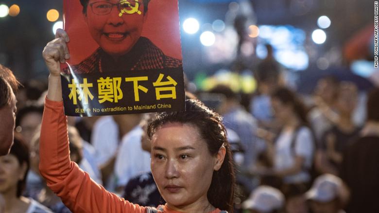 A woman holds a poster of Hong Kong Chief Executive Carrie Lam, against a proposed extradition law, before a candlelight vigil at Victoria Park in Hong Kong on June 4, 2019.