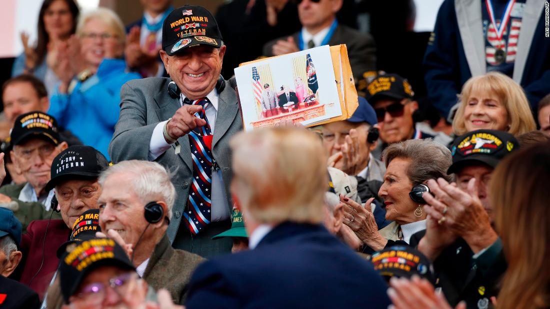A World War II veteran shows Trump a photo of himself with the President.