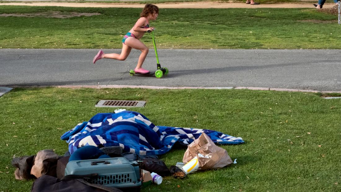 A child rides her scooter past a homeless person in Santa Monica on June 3.